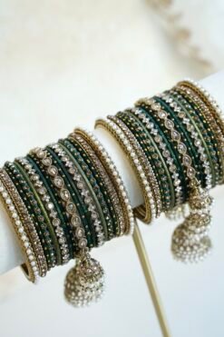 Emerald green jhumka bangle set with thread-wrapped green bangles, stone bangles, pearl-style edge bangles, and jhumka charms on a display stand