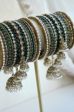 Emerald green jhumka bangle set with thread-wrapped green bangles, stone bangles, pearl-style edge bangles, and jhumka charms on a display stand