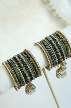 Emerald green jhumka bangle set with thread-wrapped green bangles, stone bangles, pearl-style edge bangles, and jhumka charms on a display stand