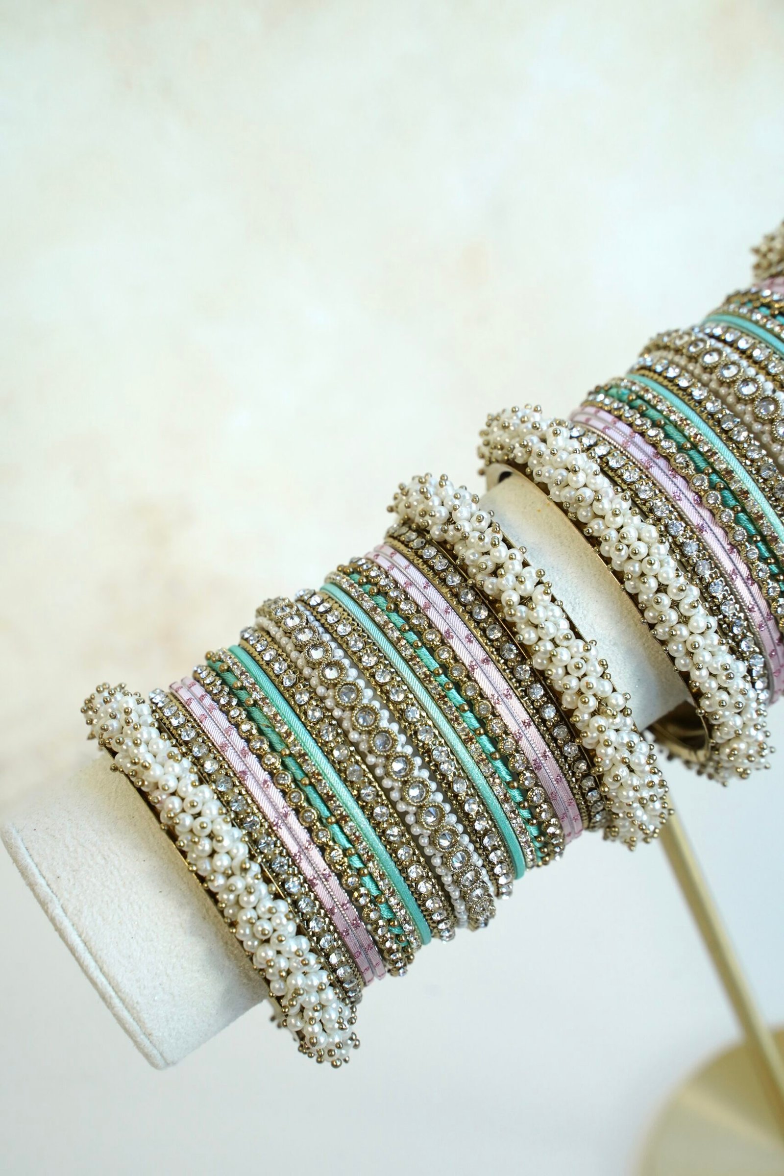 Meenal pastel bangle set with mint and lilac pink bangles, stone-lined bands and pearl-style bead edges stacked on a display stand