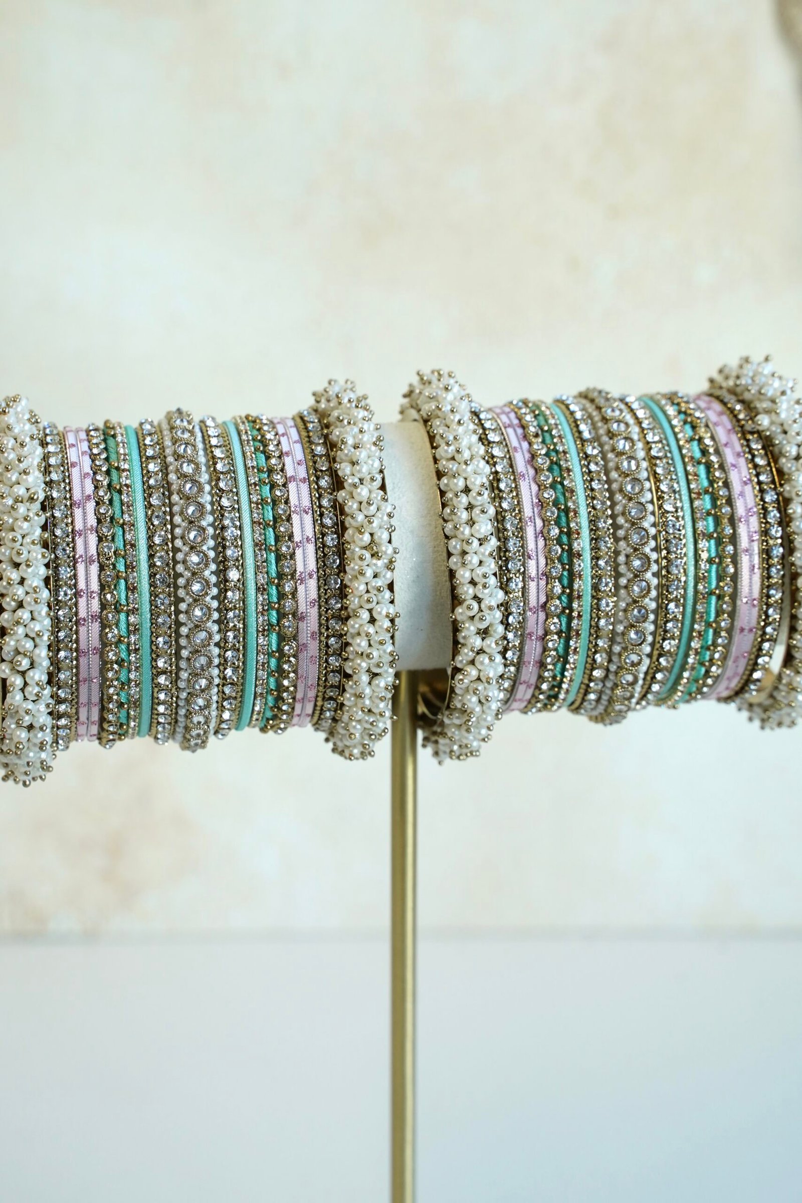 Meenal pastel bangle set with mint and lilac pink bangles, stone-lined bands and pearl-style bead edges stacked on a display stand