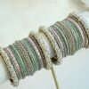 Meenal pastel bangle set with mint and lilac pink bangles, stone-lined bands and pearl-style bead edges stacked on a display stand