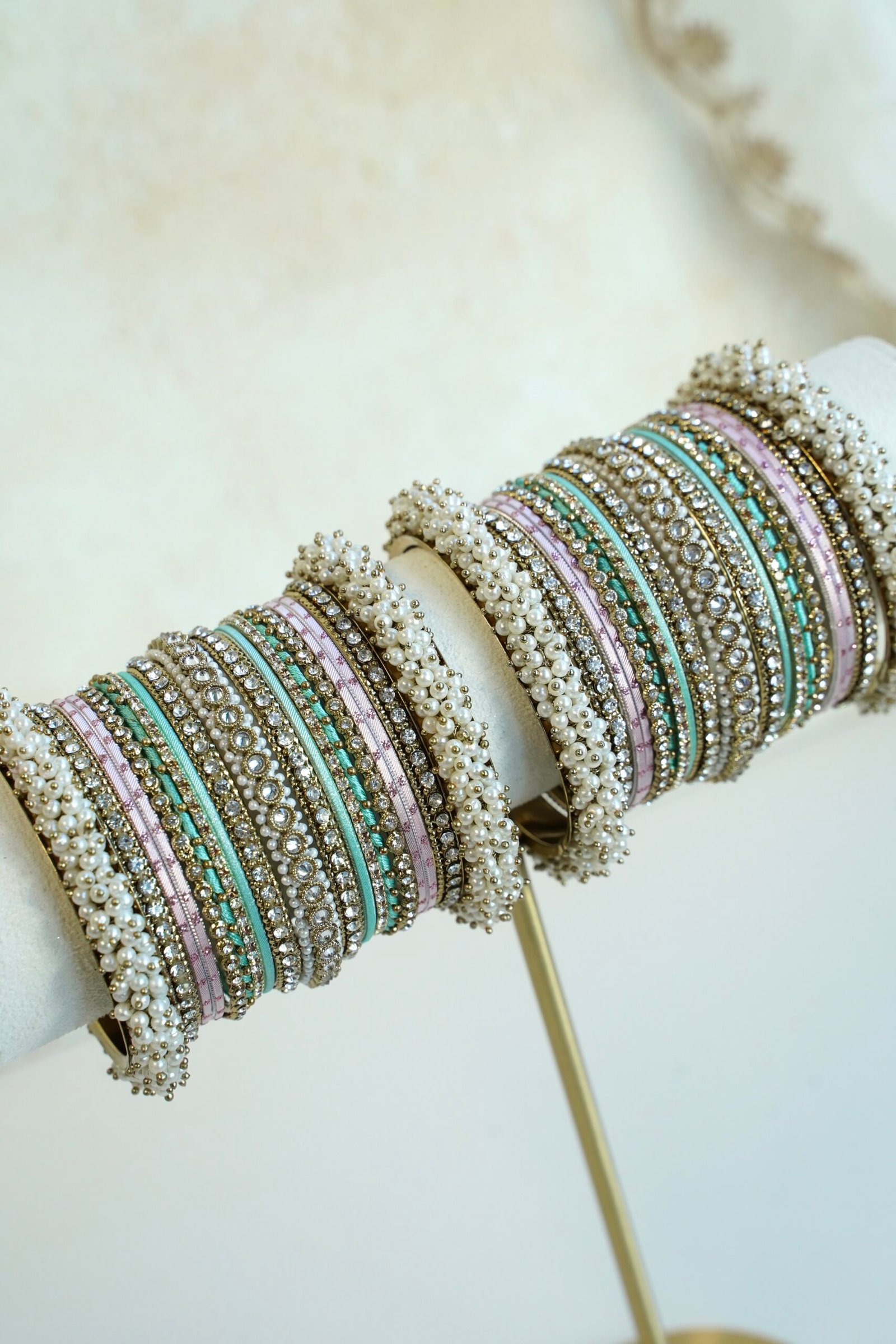 Meenal pastel bangle set with mint and lilac pink bangles, stone-lined bands and pearl-style bead edges stacked on a display stand