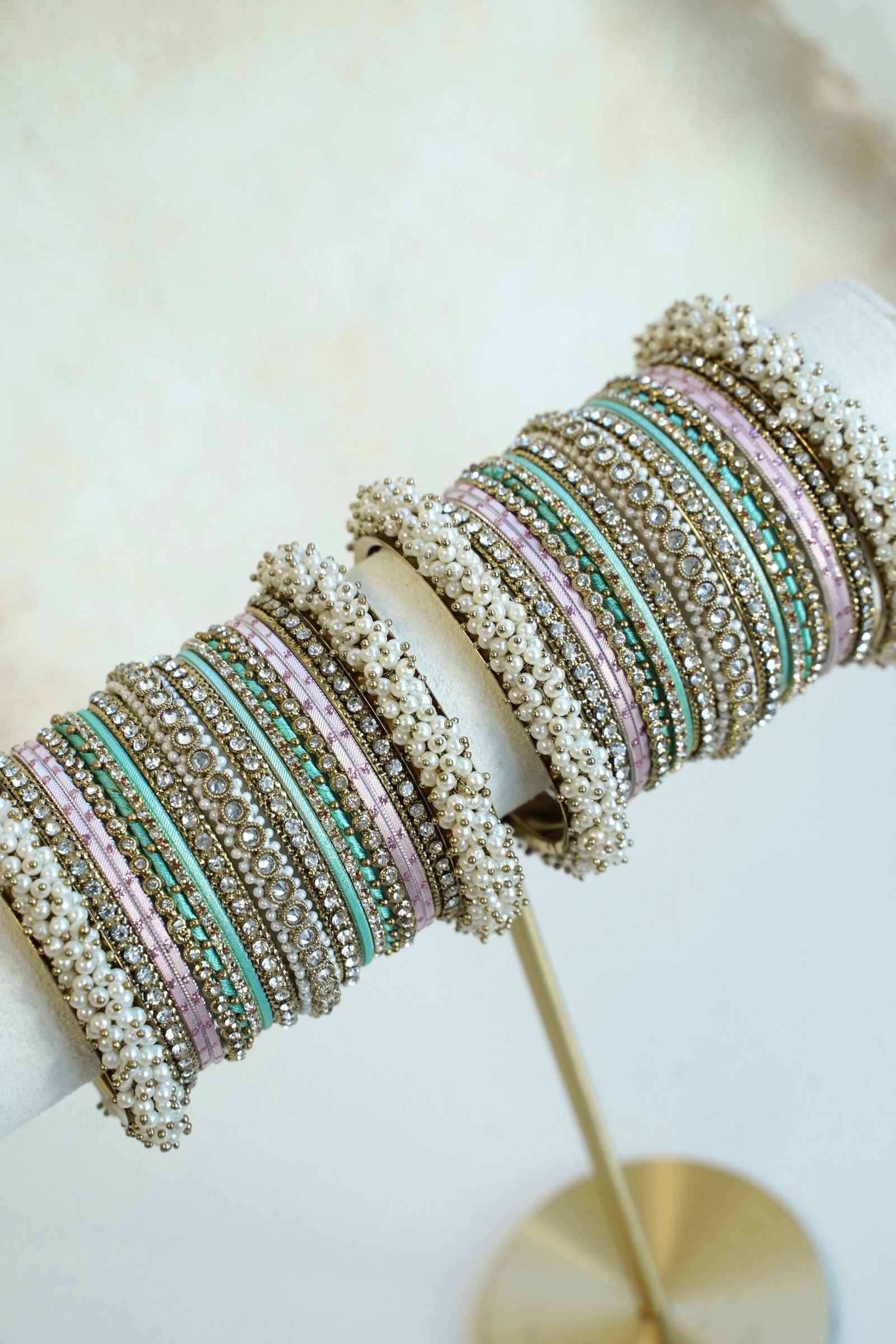 Meenal pastel bangle set with mint and lilac pink bangles, stone-lined bands and pearl-style bead edges stacked on a display stand