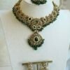 Mehr necklace set in green with antique gold-tone paisley necklace, green teardrop stones, pearl-style beads, matching earrings, and tikka on a display bust