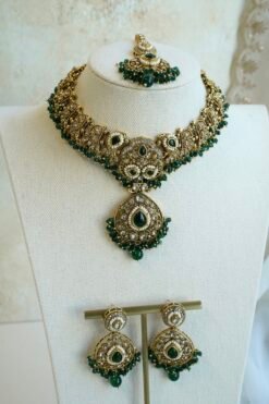 Mehr necklace set in green with antique gold-tone paisley necklace, green teardrop stones, pearl-style beads, matching earrings, and tikka on a display bust
