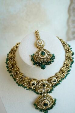 Mehr necklace set in green with antique gold-tone paisley necklace, green teardrop stones, pearl-style beads, matching earrings, and tikka on a display bust