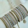 Pastel blush pink and dove gray stacked bangle set with beaded edges, champagne teardrop stones, and hanging jhumka charms