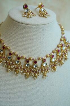 Pink pachi pearl drop necklace set with pink and clear stones, pearl-style bead clusters and matching earrings displayed on a bust