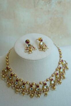 Pink pachi pearl drop necklace set with pink and clear stones, pearl-style bead clusters and matching earrings displayed on a bust