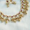 Pink pachi pearl drop necklace set with pink and clear stones, pearl-style bead clusters and matching earrings displayed on a bust
