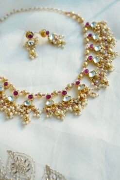 Pink pachi pearl drop necklace set with pink and clear stones, pearl-style bead clusters and matching earrings displayed on a bust