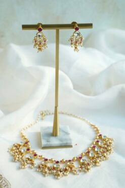 Pink pachi pearl drop necklace set with pink and clear stones, pearl-style bead clusters and matching earrings displayed on a bust