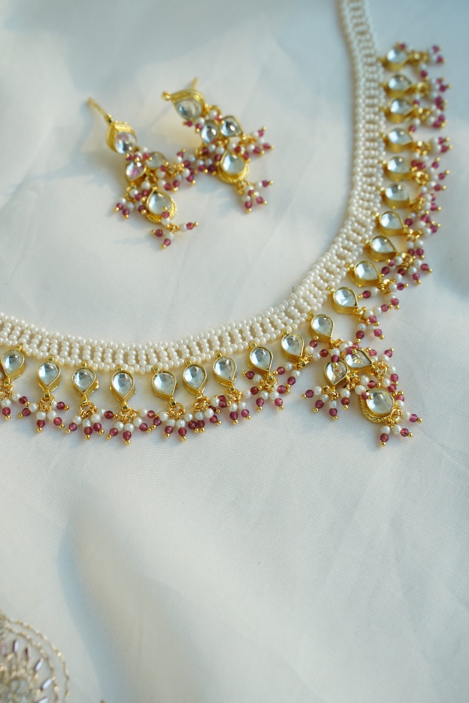 Small pachi necklace set with woven beaded neckline, clear teardrop stones, wine red bead drops, and matching earrings