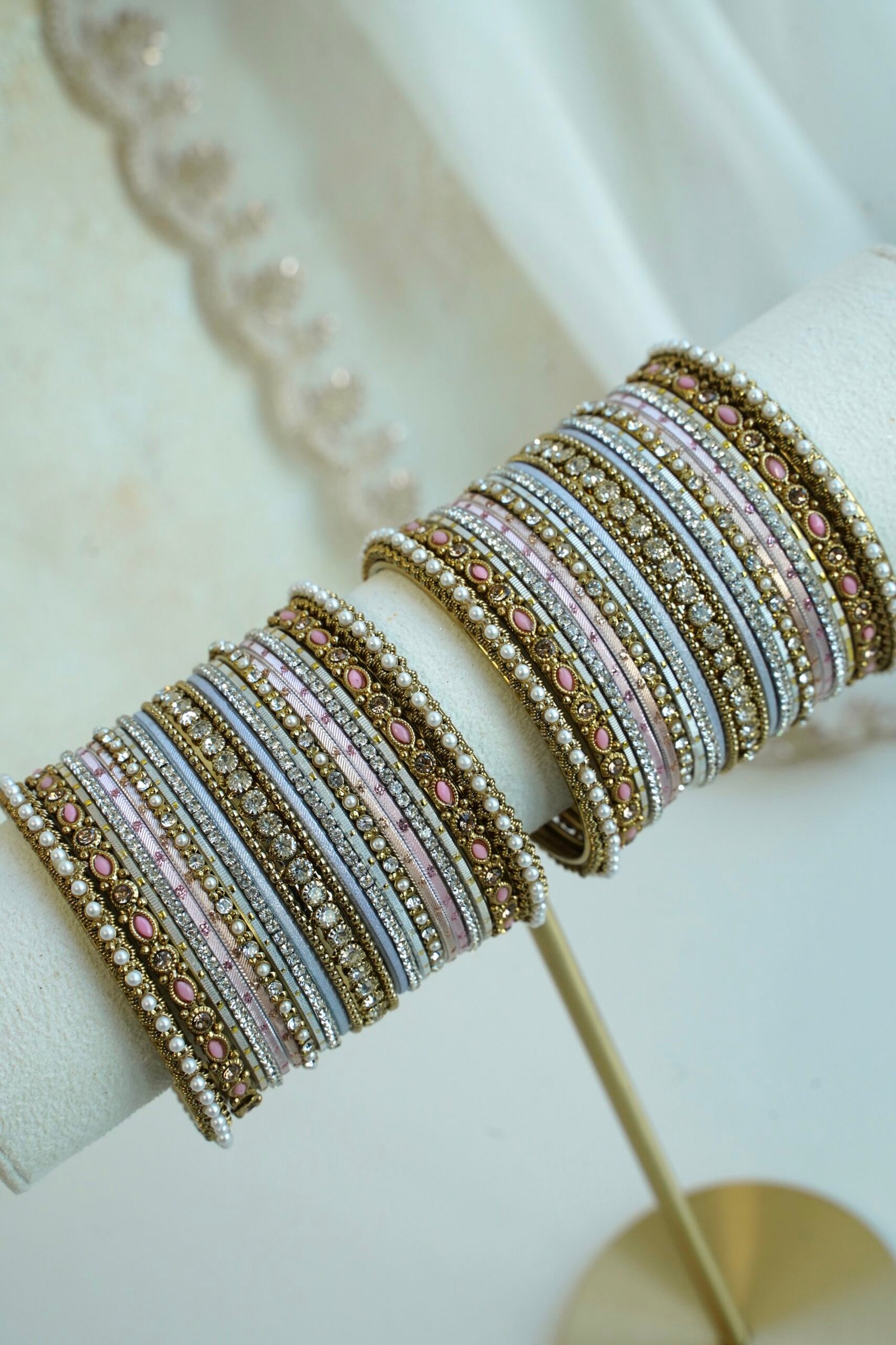 Soft pastel blush pink and blue stacked bangle set with beaded edges, stone strips, and antique gold bangles with pink oval stones