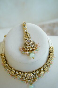 Somya pastel beaded artificial kundan set with mint and pink beads, antique gold necklace, matching earrings and tikka displayed on a bust
