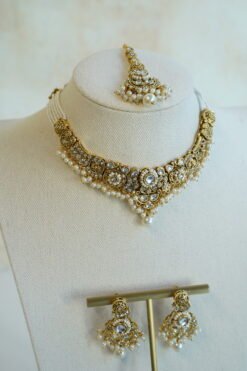 Somya white beaded artificial kundan set with antique gold necklace, pearl-style beads and clear stones, matching earrings and tikka displayed on a bust
