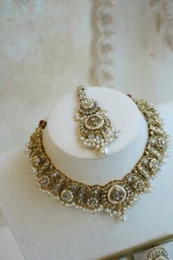 Urvi artificial kundan set with antique gold tone necklace, pearl-style bead fringe, matching earrings and tikka displayed on a bust