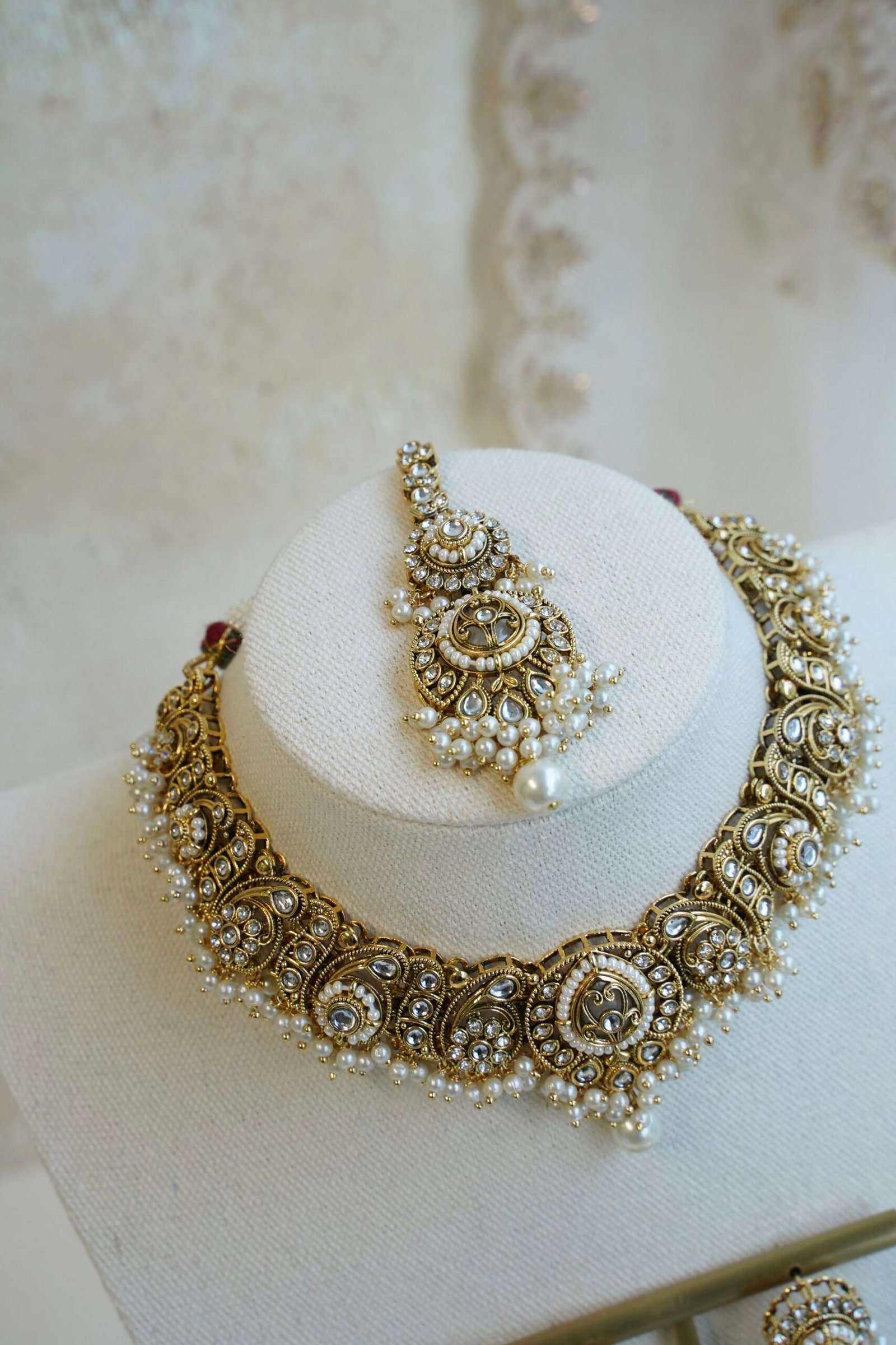 Urvi artificial kundan set with antique gold tone necklace, pearl-style bead fringe, matching earrings and tikka displayed on a bust